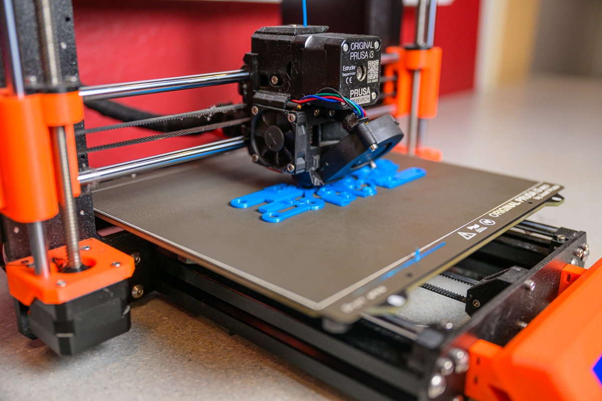 3D printer churns out plastic components.<br>